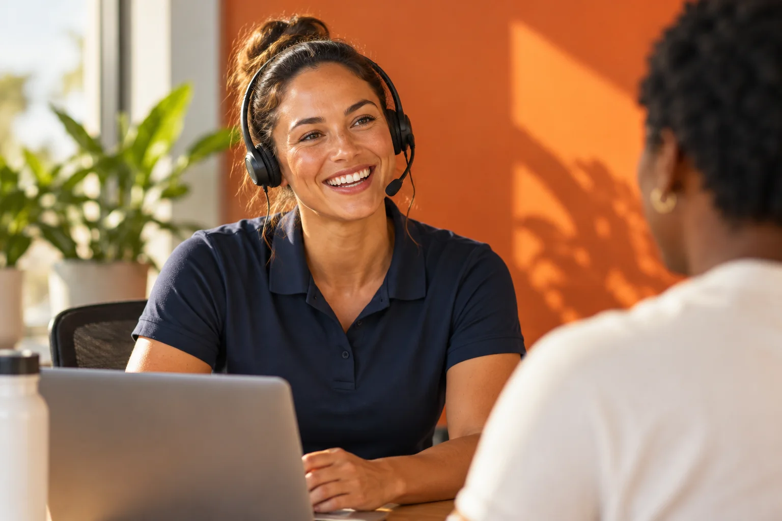Support team member with a headset smiling at a colleague
